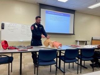 Instructor showing how to insert mouth device into CPR manikin